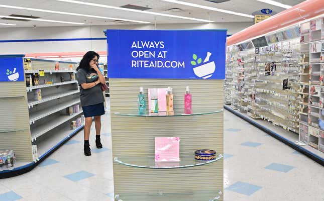 A woman looks at what items are left near empty shelves at a Rite Aid store in Alhambra, California, on October 18, 2023. 