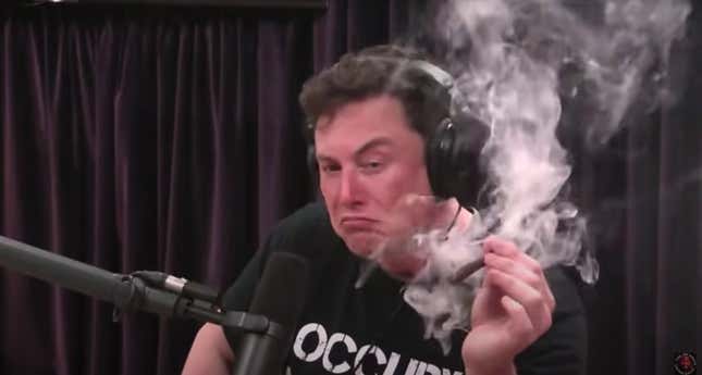 Elon Musk in a black t-shirt smirking after taking a long drag on a large marijuana joint.