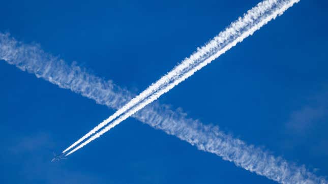 An airplane leaves contrails in the blue sky.