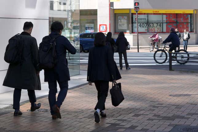 Person walk near an electronic stock board showing Japan&#39;s Nikkei 225 index at a securities firm Wednesday, March 27, 2024, in Tokyo. Asian shares were mixed on Wednesday after Wall Street slipped a bit further from its record highs. (AP Photo/Eugene Hoshiko)