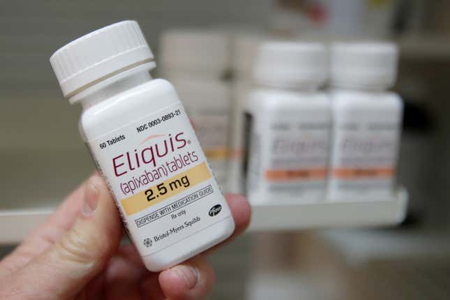 A pharmacist holds a bottle of the drug Eliquis