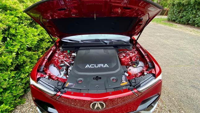 An under-hood shot of the red ZDX Type S showing a big plastic cover with ACURA written on it