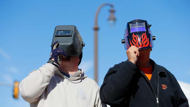 Oklahoma State Cowboys fans watch the solar eclipse through a welding helmet before a game against the Kansas Jayhawks at Boone Pickens Stadium on October 14, 2023.