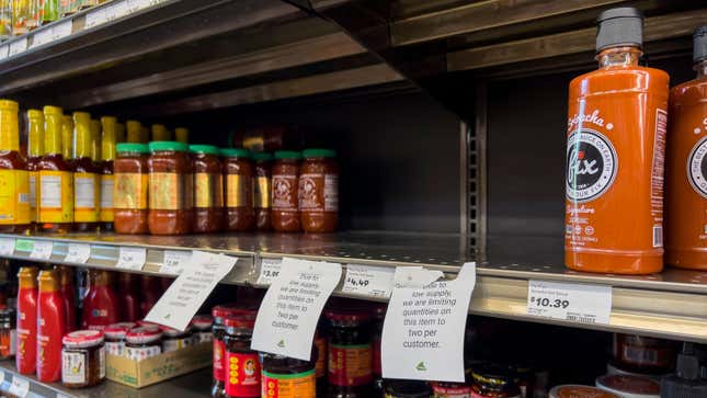 Empty store shelf with signs indicating a limit on 2 Huy Fong Sriracha bottles per person