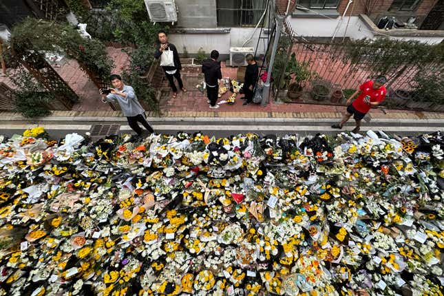 Residents take pictures as they walk by flowers laid outside a residential building where the late Chinese Premier Li Keqiang spent his childhood in Hefei city, in central China&#39;s Anhui province, Saturday, Oct. 28, 2023. The sudden death of China&#39;s former second-ranking leader, Li Keqiang, has shocked many people in the country, with tributes offered up to the ex-official who promised market-oriented reforms but was politically sidelined. (Chinatopix via AP)