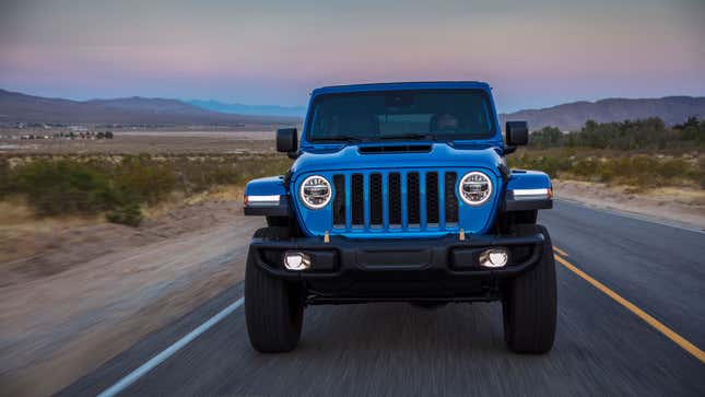 A blue Jeep Wrangler Rubicon driving down a road. 