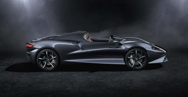 A dark gray McLaren Elva in a studio from the side view