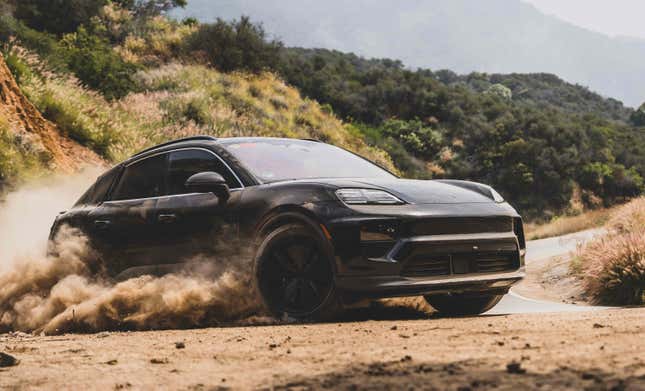 Front 3/4 view of a camouflaged black Porsche Macan EV driving on dirt