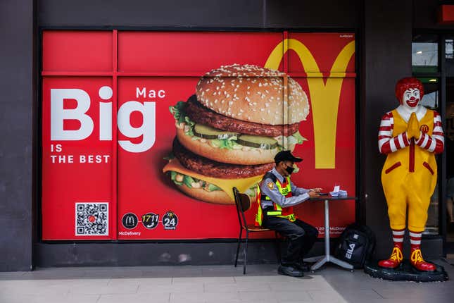 A parking lot security officer sits by an advertisement for a Big Mac in Bangkok, Thailand. International fast food chains such as McDonald’s and Burger King are wildly popular in Southeast Asia, with the brands found in nearly every major city and town in the region.