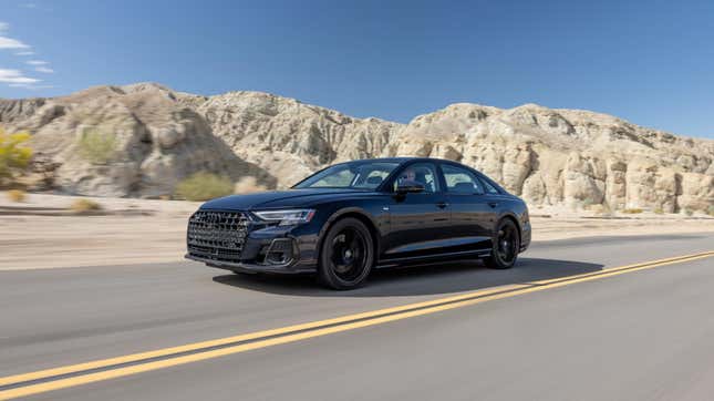 A dark blue Audi S8 driving in front of some white rocks