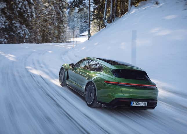 Un Porsche Taycan Turbo S Sport Turismo en verde conduciendo por una carretera nevada