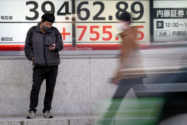 FILE - A person stands in front of an electronic stock board showing Japan&#39;s Nikkei 225 index at a securities firm Monday, March 18, 2024, in Tokyo. Shares are mixed in Asia after the Bank of Japan hiked its benchmark interest rate for the first time in 17 years, ending a longstanding negative rate policy.(AP Photo/Eugene Hoshiko, File)