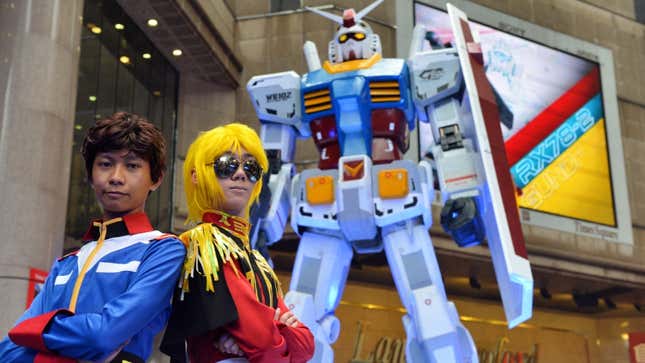 Cosplayers in Hong Kong pose in front of a giant Gundam. 