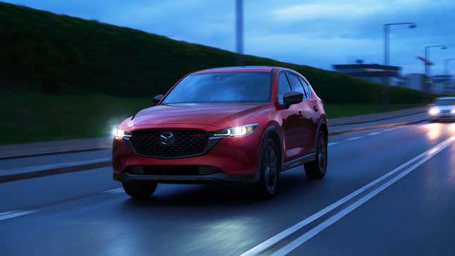 A photo of a red Mazda SUV driving on a dark road. 