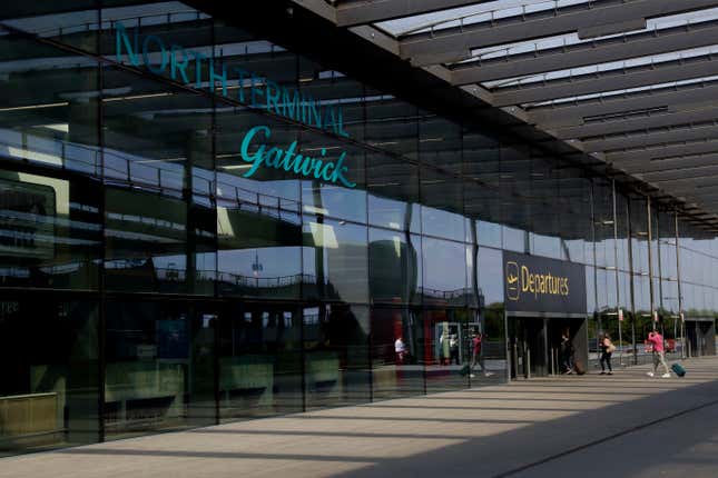 FILE - Passengers walk into the Departures entrance at the North Terminal of Gatwick Airport near Crawley, just south of London, Wednesday, July 22, 2020. Gatwick Airport, London’s second-busiest, is limiting flights this week, partly because of an outbreak of COVID-19 within air traffic control. In a statement late Monday, Sept. 25, 2023 the airport says a daily limit of 800 flights has been imposed until Sunday, affecting both departures and arrivals. (AP Photo/Matt Dunham, File)