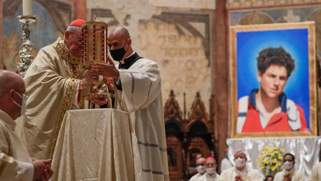 Cardinal Agostino Vallini, left, holds a relic of 15-year-old Carlo  Acutis, an Italian boy who died in 2006 of leukemia, during his  beatification ceremony celebrated in the St. Francis Basilica, in  Assisi, Italy on Oct. 10, 2020. 