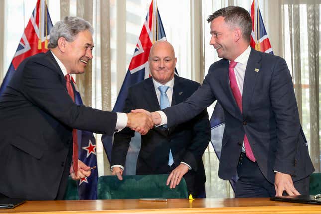 New Zealand Prime Minister elect Christopher Luxon, centre, watches as his coalition partners, New Zealand First leader Winston Peters, left, and ACT leader David Seymour shake hands following a signing ceremony in Wellington, New Zealand, Friday, Nov. 24, 2023. New Zealanders can expect tax cuts, more police on the streets and reductions to government bureaucracy, according to the three leaders who signed an agreement Friday to form a new government. The coalition deal ended nearly six weeks of intense negotiations after New Zealand held a general election on Oct. 14. (Mark Mitchell/NZ Herald via AP)