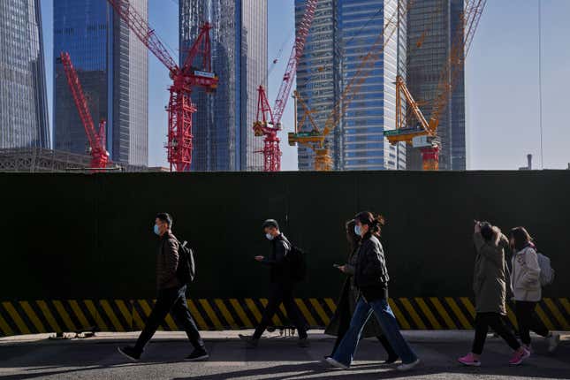 FILE - People wearing face masks walk by construction cranes near the office buildings at the central business district in Beijing, on March 15, 2023. Chinese leaders have held an annual planning meeting where they agreed to step up spending to help rev up the world&#39;s second-largest economy, state media reported Friday Dec. 8, 2023 without giving details of any policy changes. The report gave few specifics on how the leadership plans to handle fast mounting debts and resolve a crisis in the vital property sector after defaults by dozens of developers. (AP Photo/Andy Wong, File)