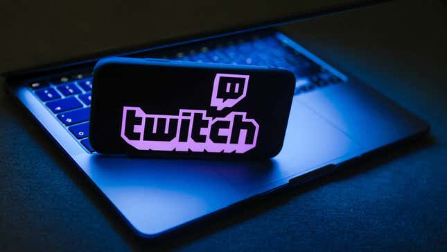 The Twitch logo is displayed on a phone screen, which is stood atop a laptop's keyboard.