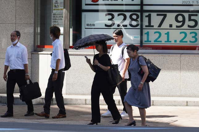 FILE - People walk in front of an electronic stock board showing Japan&#39;s Nikkei 225 index at a securities firm on Sept. 5, 2023, in Tokyo. Shares fell Friday, Sept. 8 in Asia after Japan reported its economy grew less than earlier estimated in the last quarter. (AP Photo/Eugene Hoshiko, File)