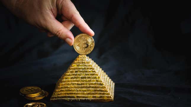 a finger holds a gold coin bitcoin on top of the pyramid on a black background.