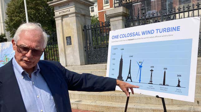 David Stevenson, policy director at the Caesar Rodney Institute and former Trump adviser, points to a placard that features images of landmarks and a wind turbine, while facing reporters Wednesday, Aug. 25, 2021, in front of the Statehouse, in Boston.