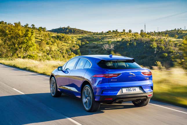 Rear-quarter image of a blue Jaguar i-Pace on a road.