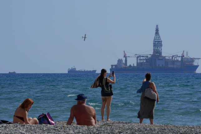 FILE - People on the beach take photos of the &#39;Tungsten Explored&#39; drilling ship, in the southern coastal city of Larnaca, Cyprus, on Nov. 3, 2021. The Cyprus government and U.S. energy company Chevron have reached a deal on how to develop the Aphrodite gas field, the first to be discovered under the seafloor off Cyprus, an official said Friday, Dec. 1, 2023. The field is estimated to hold 4.2 trillion cubic feet of gas. (AP Photo/Petros Karadjias, File)