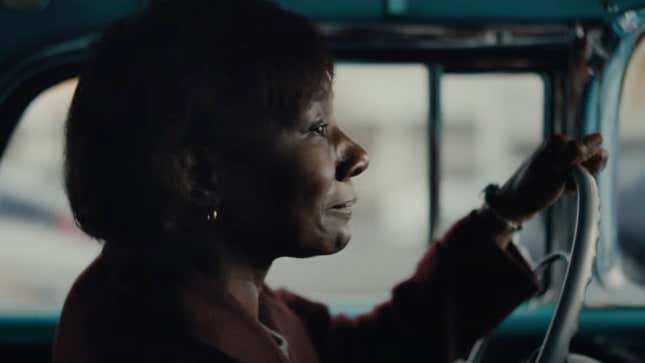 interior shot of an older Black woman behind the wheel of a teal 1957 chevrolet nomad