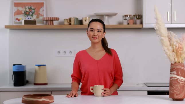 avatar of woman wearing a pink shirt standing in a kitchen