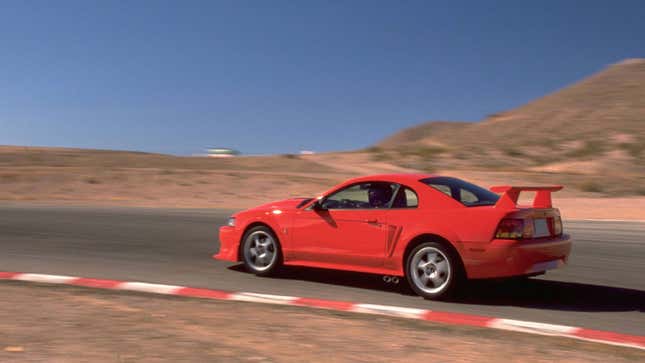 A photo of a red Ford Mustang on a track. 