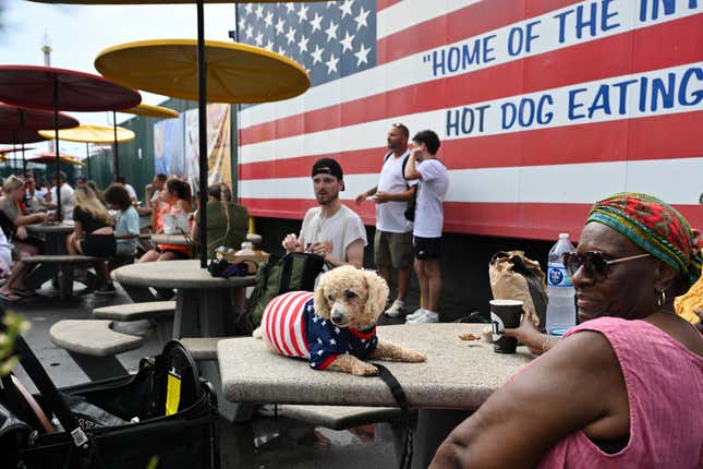 Une femme est assise avec son chien, vêtue d’un costume de drapeau américain, au coin salon du célèbre Hot-Dog international du 4 juillet de Nathan. Concours de restauration à Coney Island à Brooklyn, New York.