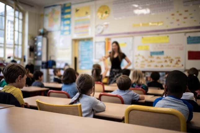 TOPSHOT - Children listen to their teacher as they sit in a classroom on the first day of the start of the school year, at the Chaptal elementary school in Paris, on September 2, 2019. - In France some 12.4 million students crossed the doors of elementary schools (6.7 million), secondary school (3.4 million) and high schools (2.3 million) on September 2, 2019. (Photo by Martin BUREAU / AFP) (Photo credit should read MARTIN BUREAU/AFP via Getty Images)