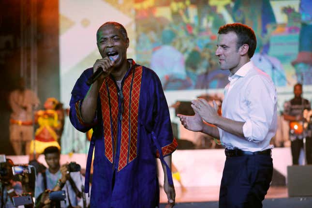 French President Emmanuel Macron (R) stands on stage as Nigerian musician Femi Kuti performs during Macron’s visit to the Afrika Shrine.