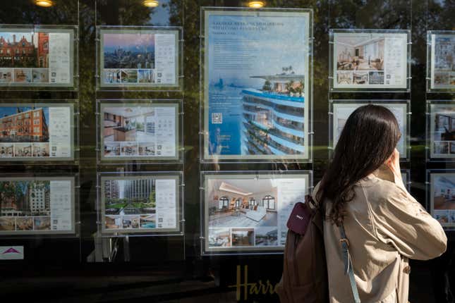 A woman walks by a window with real estate ads.