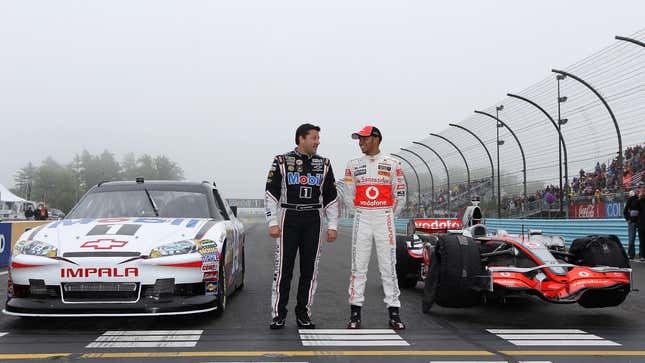 Lewis Hamilton of England, driver of the Vodafone McLaren Mercedes MP4-23, poses for photographers alongside Tony Stewart, driver of the #14 Mobil 1/Office Depot Chevrolet, during the Mobil 1 Car Swap at Watkins Glen International on June 14, 2011 in Watkins Glen, New York.