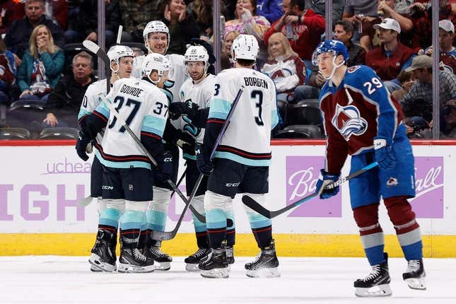 Nov 9, 2023; Denver, Colorado, USA; Seattle Kraken right wing Oliver Bjorkstrand (22) celebrates his goal with center Yanni Gourde (37) and right wing Eeli Tolvanen (20) and defenseman Jamie Oleksiak (24) and defenseman Will Borgen (3) as Colorado Avalanche center Nathan MacKinnon (29) skates by in the second period at Ball Arena.