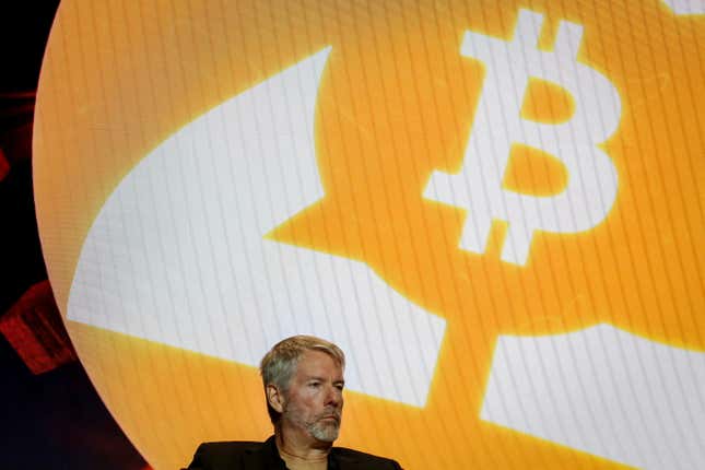 A man in front of a screen with a bitcoin symbol