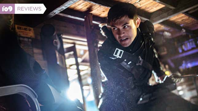 Henry Golding as Snake Eyes in Snake Eyes: G.I. Joe Origins leans down while wielding his sword and wearing all black.