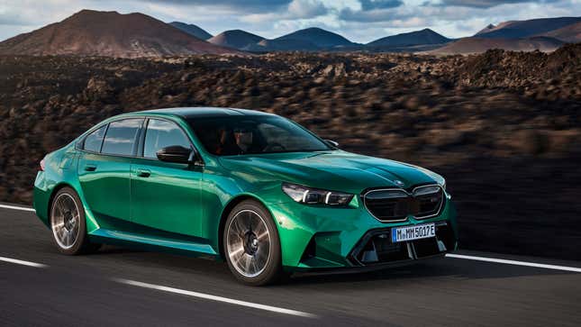 A green M5 from the front 3/4 angle driving in front of a desolate landscape