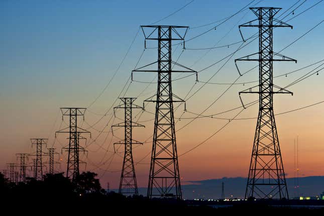 power transmission lines hanging on electricity pylons, the sun is setting in the background