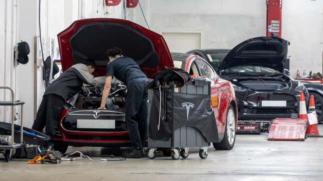 Two mechanics work on a Tesla.