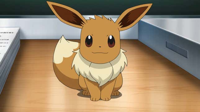 An Eevee sits on a desk next to a stack of papers.