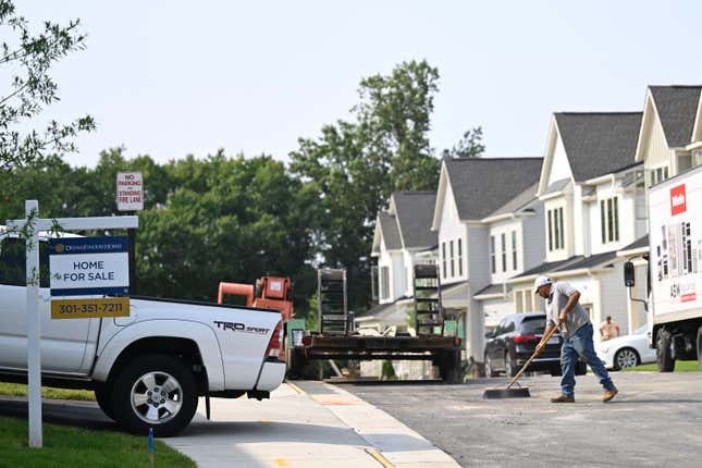 A "For Sale" sign is displayed in front of a new home in a housing development