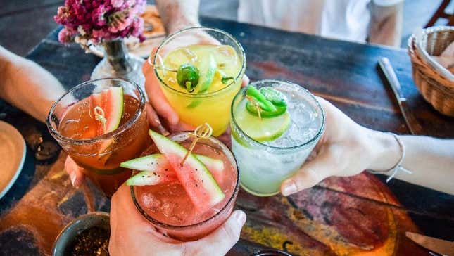 Four cocktail glasses raised in a toast