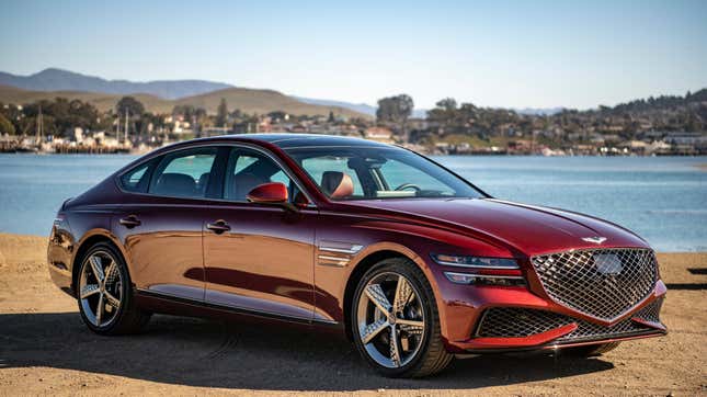 A dark red Genesis G80 parked in front of a body of water