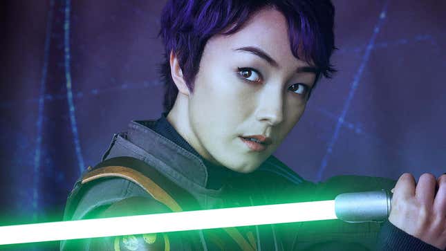 Une image montre Sabine Wren avec les cheveux courts et tenant un sabre laser vert. 