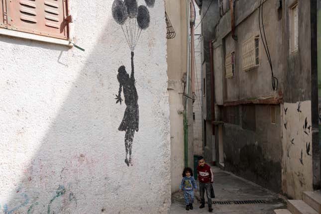 Palestinian children walk in an alley of the Aida Refugee Camp, near the health clinic and school run by the the United Nations Relief and Works Agency for Palestinian Refugees in the Near East (UNRWA) in the West Bank city of Bethlehem, Tuesday, Feb. 20, 2024. (AP Photo/Maya Alleruzzo)