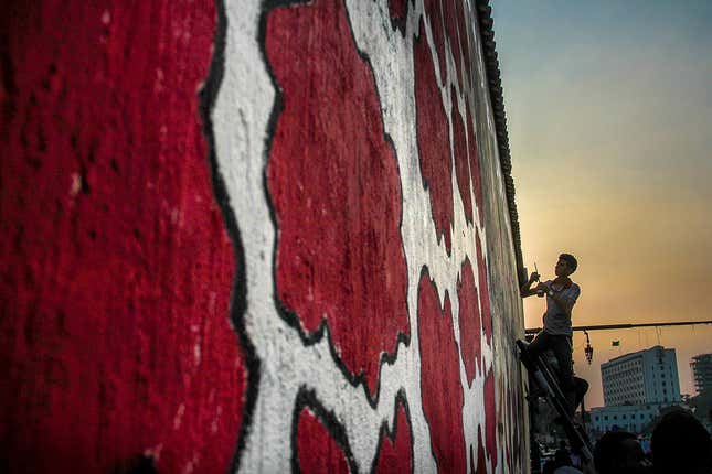 A graffiti artist painting graffiti on a wall near Tahrir square.