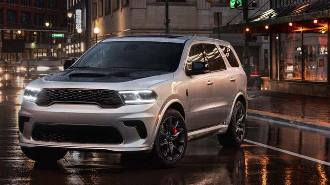 A silver 2025 Dodge Durango parked on a rainy city street at night